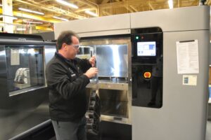 Fleet Readiness Center Southeast tool designer Randy Meeker removes a part he printed on the plant’s new Fortus 900 3D printer on Feb. 13, 2018 (Photo: U.S. Navy by Clifford Davis)